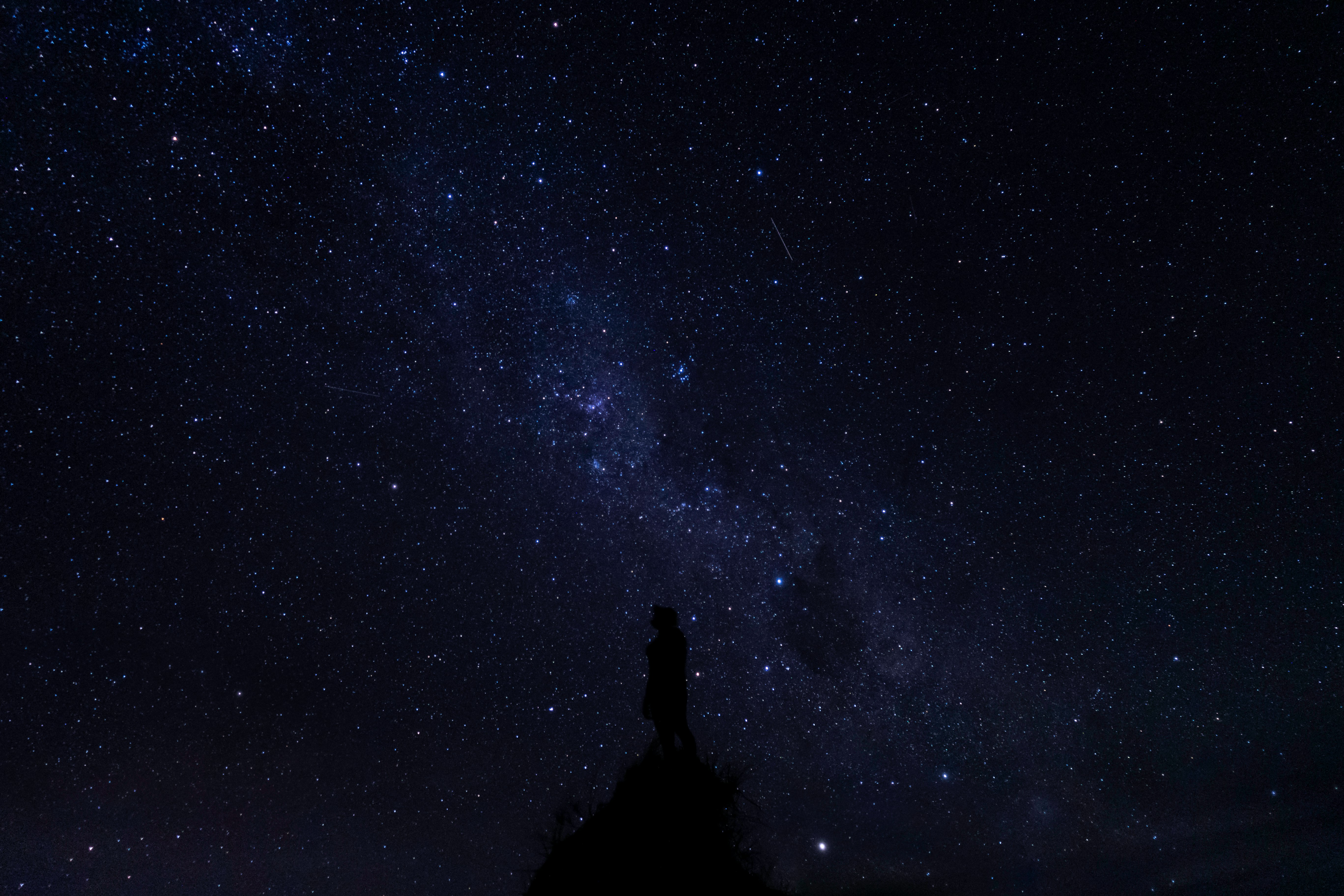 silhouette of man standing under starry night